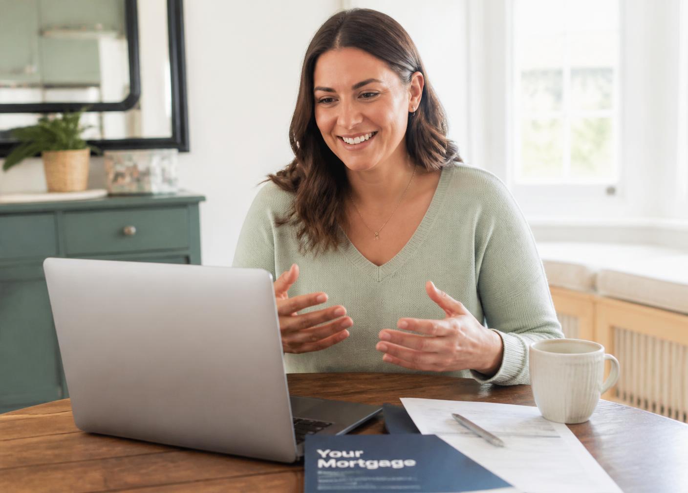 A client speaking to an adviser on a video call from her kitchen table